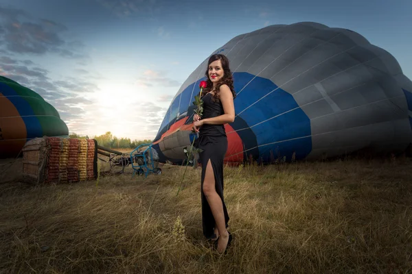 Junge Frau posiert auf Wiese neben Heißluftballons — Stockfoto