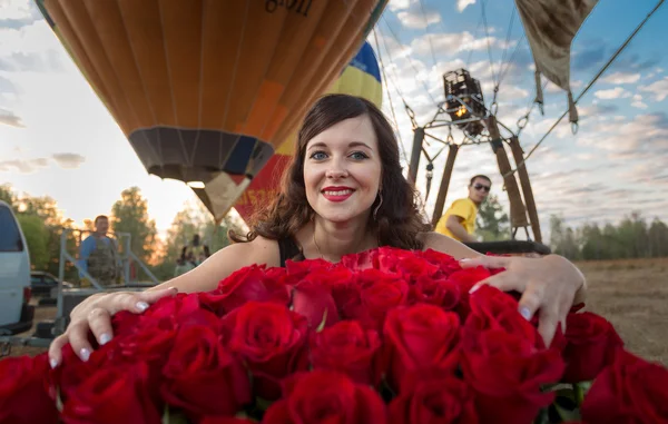 Brunette woman posing with bouquet of roses against hot air ball — Stock Photo, Image