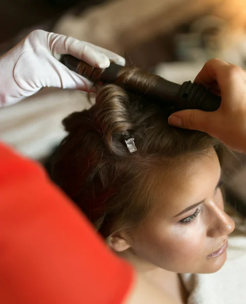 Closeup of hairstylist using curling iron on beautiful blonde wo — Stock Photo, Image