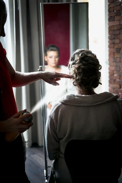 Hairstylist using hairspray on blonde bride's hair — Stock Photo, Image