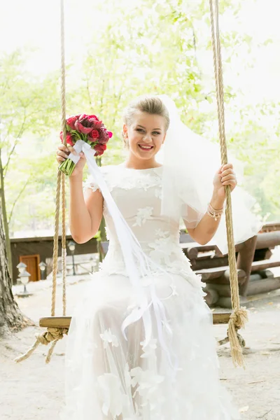 Portrait tonique de belle mariée balançant sur balançoire au parc — Photo