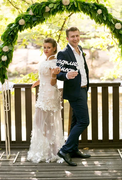 Beautiful bride and groom posing with decorative wooden word — Stock Photo, Image