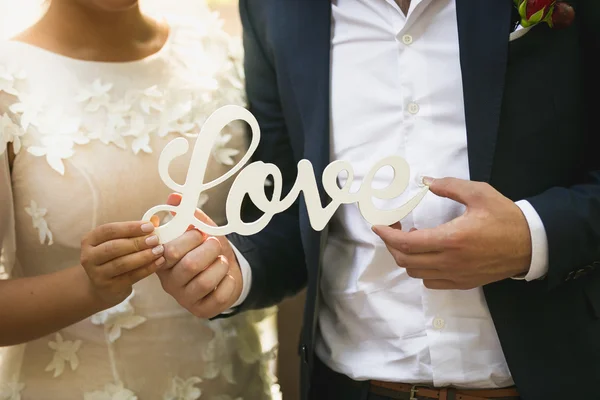 Close up of bride and groom holding word Love — стоковое фото