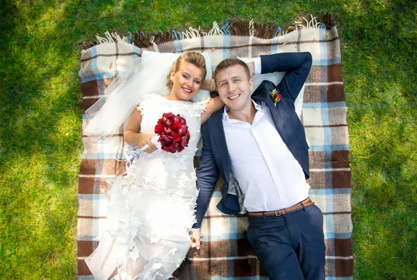 Portrait de belle mariée et marié couché sur l'herbe au parc — Photo