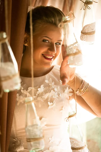 Retrato de novia rubia linda mirando a través de botellas decorativas —  Fotos de Stock