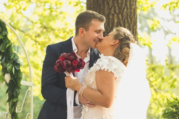 Tonas porträtt av lyckliga brudparet kysser på garden — Stockfoto