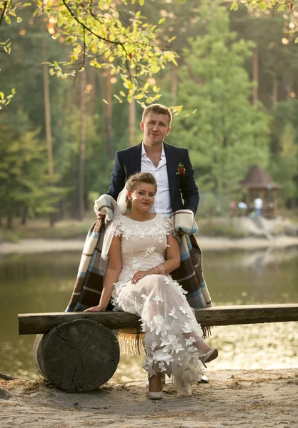 Tonas foto av brudgummen kramas bruden sitter på bänken vid strand — Stockfoto