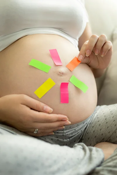 Mulher grávida arrancando memo adesivo da barriga — Fotografia de Stock