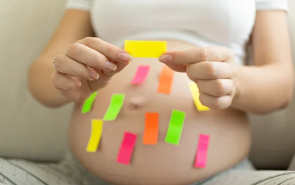 Pregnant woman holding colorful memo stickers — Stock Photo, Image