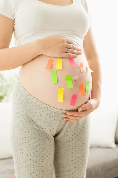 Closeup of colorful stickers on pregnant woman tummy — Stock Photo, Image