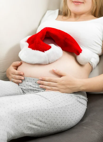 Gravid kvinna liggande på sängen med Santa mössa — Stockfoto