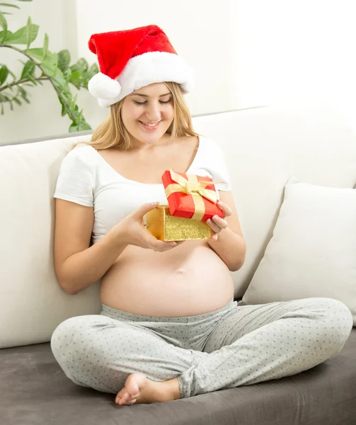 Gravid kvinna i Santa mössa ser inne i presentförpackning — Stockfoto