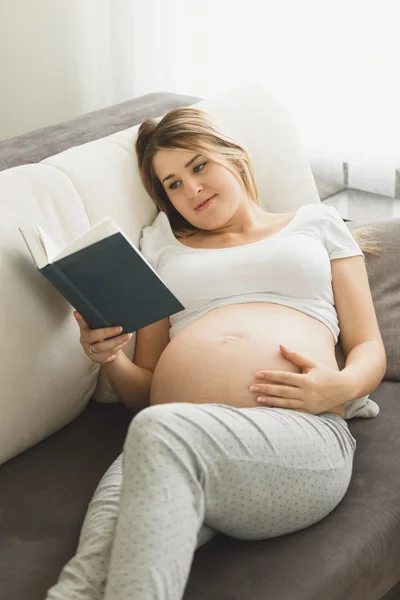 Tonas foto av gravid kvinna liggande på soffan och läsa bok — Stockfoto