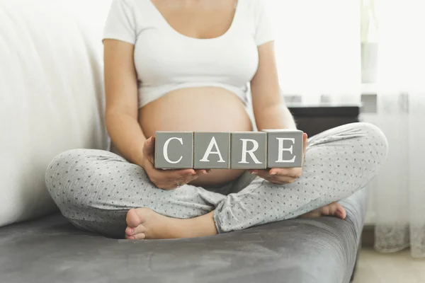 Closeup kelime bakım yapma harf tutan hamile kadın — Stok fotoğraf