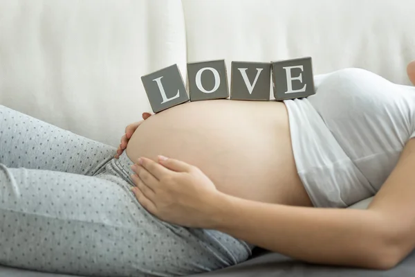 Gravid kvinna med ordet kärlek på mage — Stockfoto