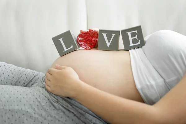 Slovo láska píše na bloky na těhotné bříško — Stock fotografie