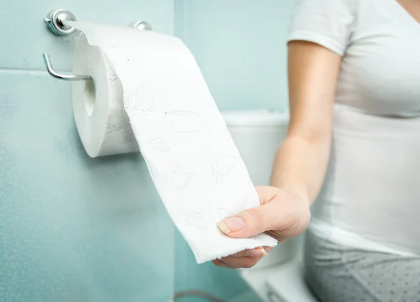 Gros plan de la femme assise sur les toilettes et utilisant du papier toilette — Photo