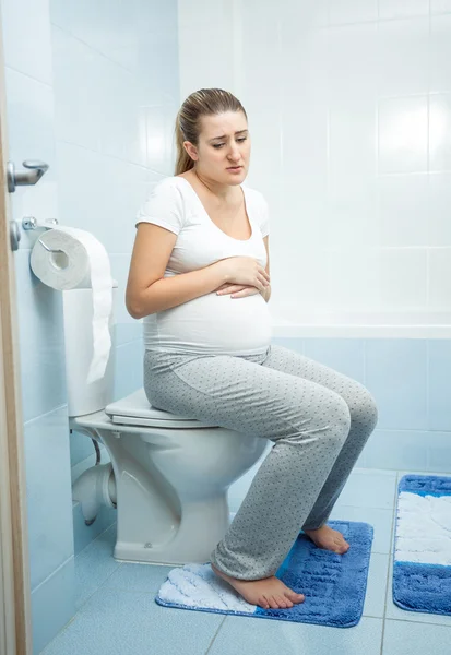 Sjuk gravid kvinna witting på toaletten — Stockfoto