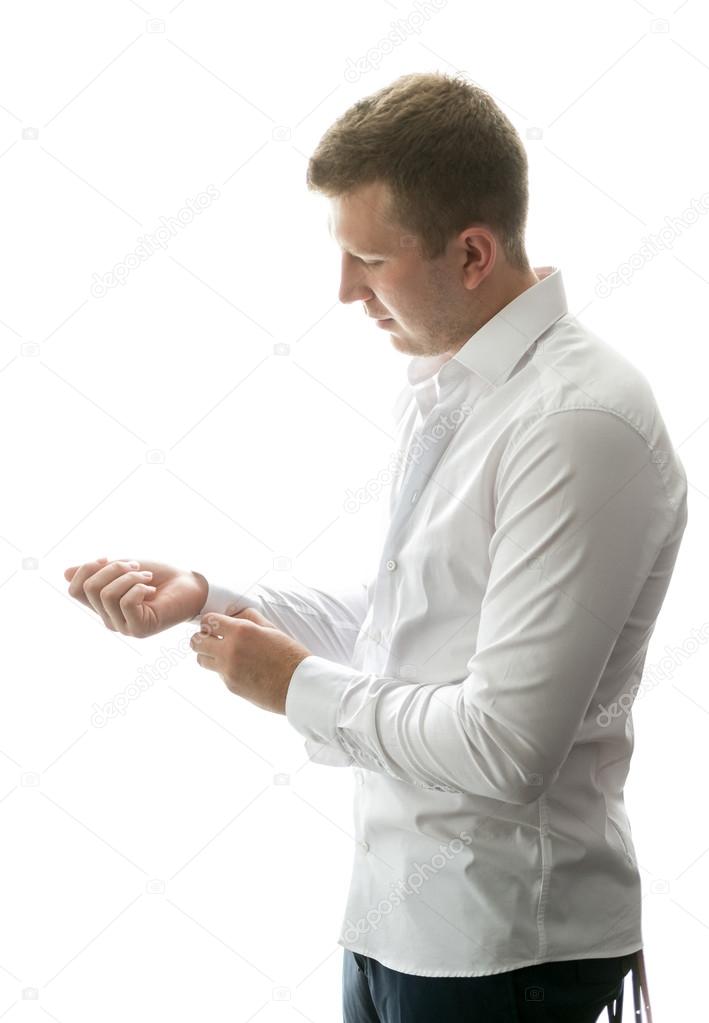 portrait of stylish man getting ready and buttoning shirt sleeve