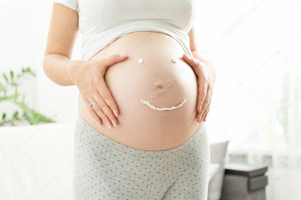 pregnant woman with smile drawn by creme for stretch marks on tu