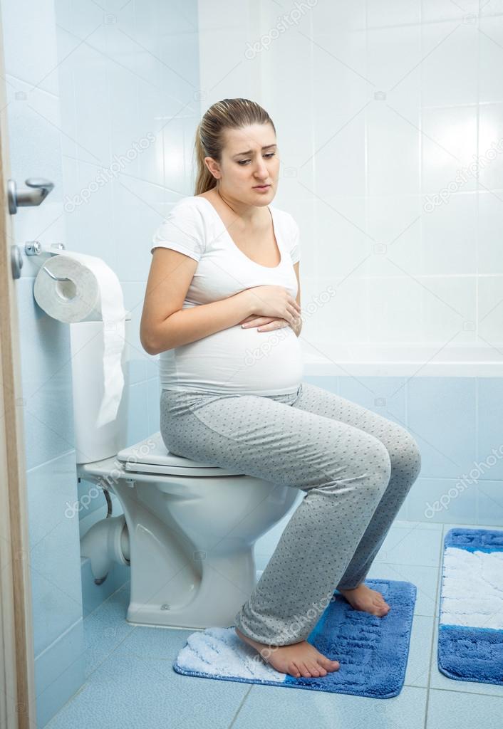 sick pregnant woman witting on the toilet