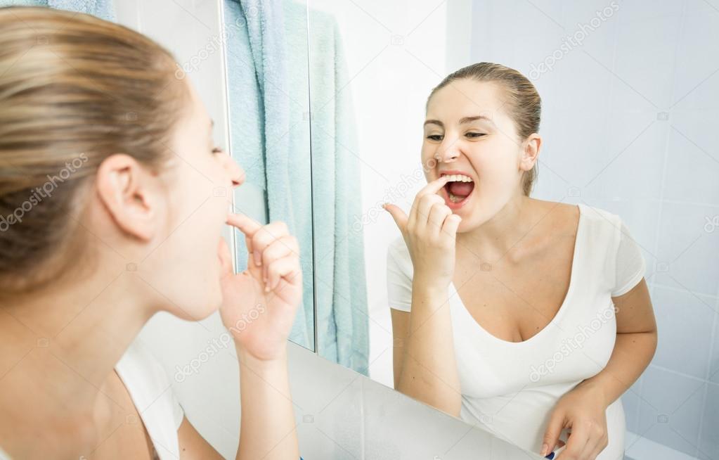 young woman picking food stuck in teeth with finger