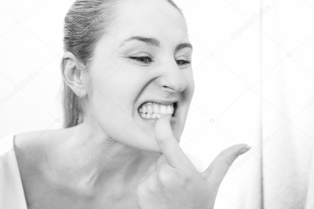 portrait of young woman looking in mirror and checking teeth