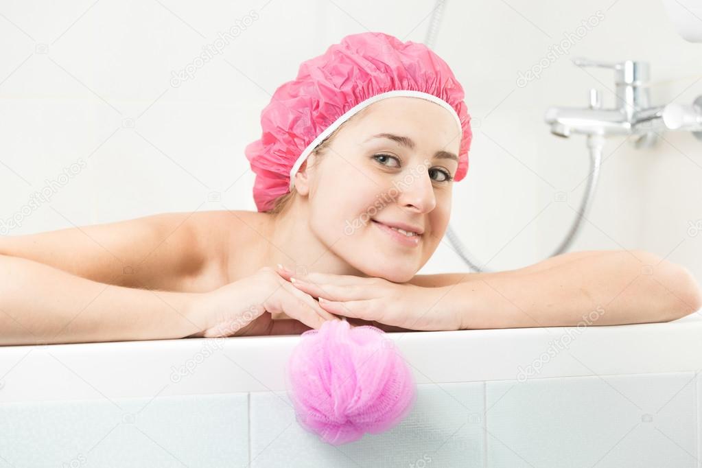 young woman in shower cap posing in bath