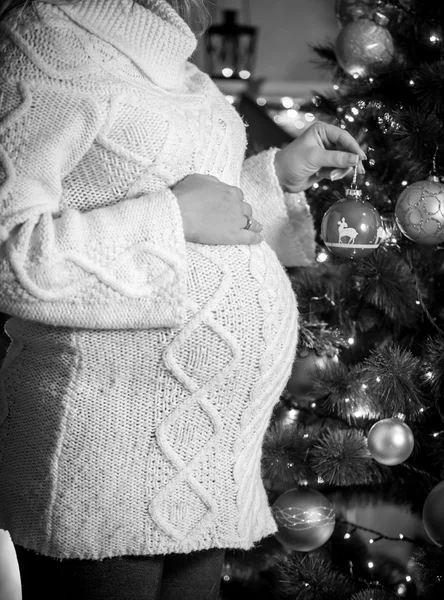 Foto monocromática de una mujer embarazada posando en el árbol de Navidad — Foto de Stock