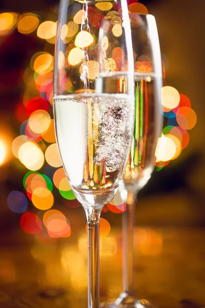 Macro of champagne poured in glasses against Christmas lights — Stock Photo, Image