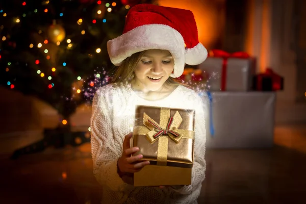 Meisje poseren met gloeiende gouden geschenkdoos — Stockfoto