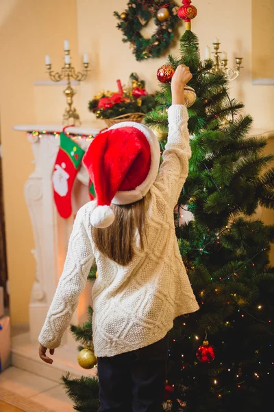 Niña poniendo bola decorativa en el árbol de Navidad — Foto de Stock
