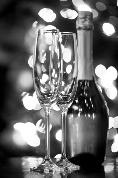 Two glasses and bottle of Champagne against Christmas lights — Stock Photo, Image