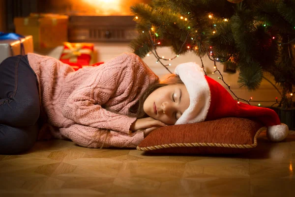 Menina dormindo no chão na lareira sob a árvore de Natal — Fotografia de Stock