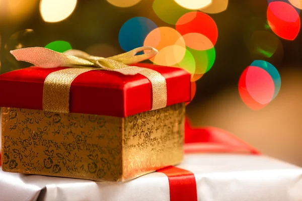 Caja de Navidad con cinta dorada sobre fondo de luz colorida —  Fotos de Stock