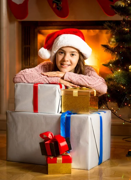 Menina sorrindo inclinando-se em caixas de presente de Natal na lareira — Fotografia de Stock