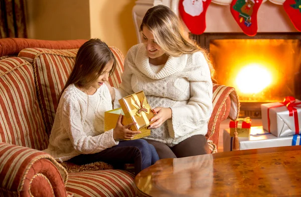 Joven madre dando hija presente en la víspera de Navidad — Foto de Stock