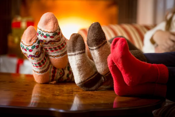 Nahaufnahme von Familienfüßen in Wollsocken am Kamin lizenzfreie Stockbilder