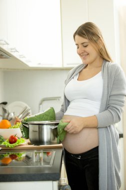 Mutfak Çorba pişirme sırasında poz gülümseyen hamile kadın