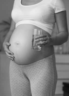 Siyah ve beyaz fotoğraf bekleyen anne holding cam su