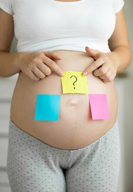 Pembe ve mavi etiket göbek üzerinde olan hamile kadın closeup