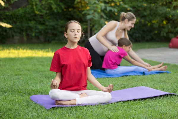 Petite fille assise dans la jeune pose sur l'herbe à la leçon de plein air — Photo