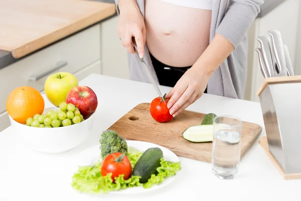 Primer plano de la mujer embarazada cortando tomates frescos para ensalada — Foto de Stock