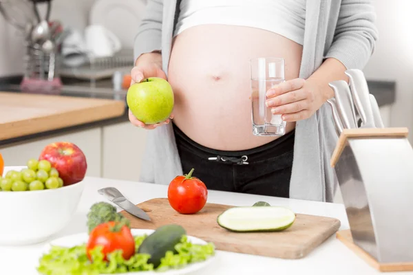 朝食にリンゴと水を持つ妊婦のクローズ アップ — ストック写真