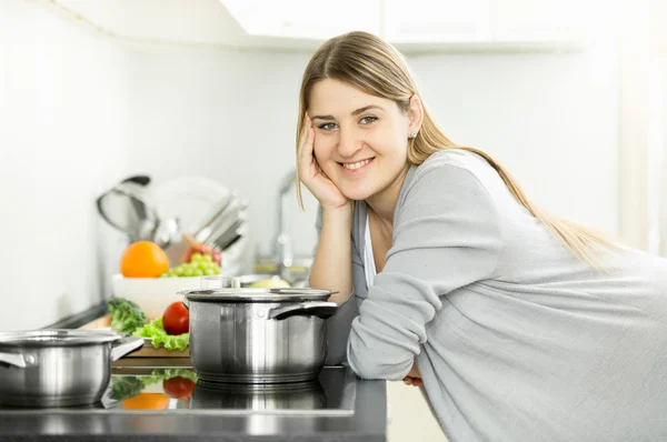 Porträt einer lächelnden Hausfrau, die in der Küche posiert und Suppe kocht — Stockfoto