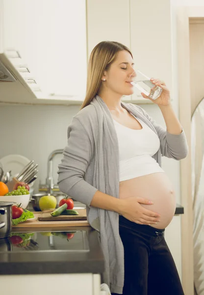 Retrato de mulher grávida bebendo água na cozinha — Fotografia de Stock