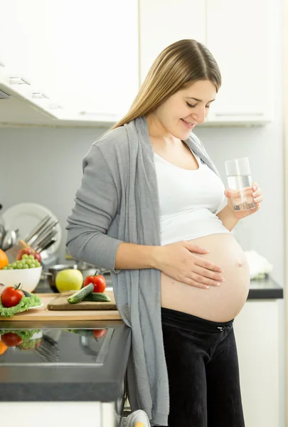 Femme enceinte au troisième trimestre posant avec un verre d'eau sur — Photo