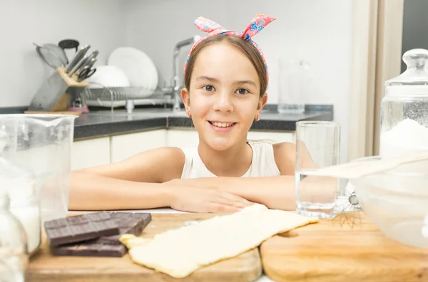 Primo piano di carina ragazza sorridente appoggiata sul piano di cottura in legno su — Foto Stock