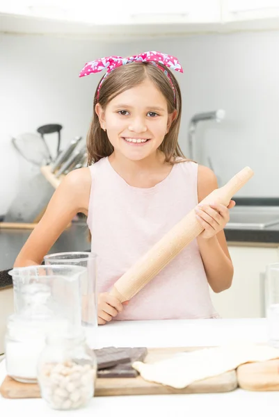 Ragazza con fiocco rosa sui capelli in posa con mattarello in legno — Foto Stock