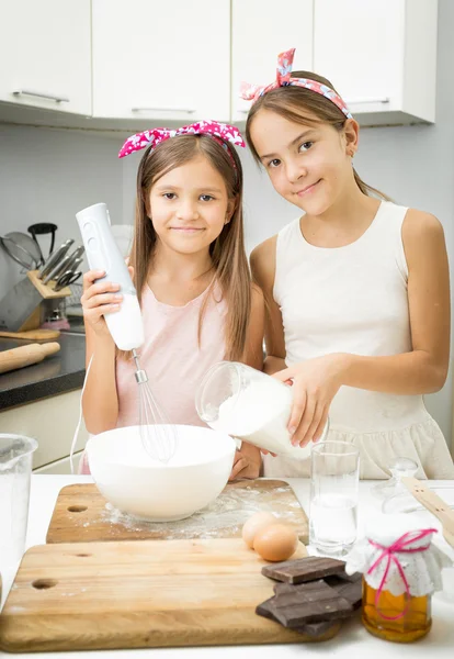 Two sister mixing ingredients for dough in big bowl on kitchen — Stock Photo, Image